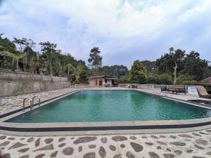 a swimming pool with green water in a yard at Omah Trasan Pangrango by ABM in Bogor