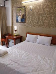a bedroom with a white bed with a picture on the wall at Khách Sạn Thiên Phúc in Ho Chi Minh City