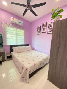 Teratak Raffa Homestay في Kampong Tebing Rabak: غرفة نوم مع جدران أرجوانية وسرير مع مروحة سقف