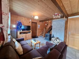 a living room with a couch and a christmas tree at Chalet chaleureux face aux pistes, proche Gérardmer, idéal pour famille, balcon et terrasse - FR-1-589-182 in Ban-sur-Meurthe-Clefcy