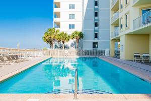 a swimming pool with chairs and a building at Boardwalk #787 in Gulf Shores