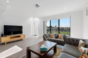 Una sala de estar con un sofá y un televisor. en 4-13 Central Dr Victor Harbor-No Linen Included, en Victor Harbor