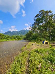 a tent on the shore of a river at Batu Ridi Jungle in Timbanglawang +19 photos