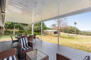 a screened in porch with a table and chairs at Deer Valley Farm Stay Illawarra sleeps up to 9 in Kembla Grange