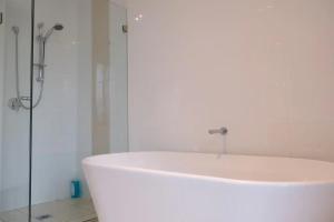 a white bath tub in a bathroom with a shower at Kellyvile Delight 5BrHouseParkingShopping Center in Kellyville
