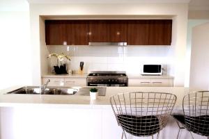 a kitchen with a sink and a counter with chairs at Kellyvile Delight 5BrHouseParkingShopping Center in Kellyville