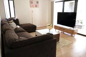 a living room with a couch and a flat screen tv at Kellyvile Delight 5BrHouseParkingShopping Center in Kellyville