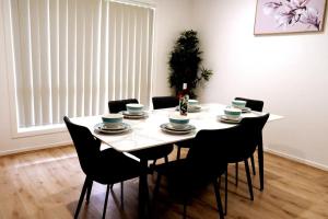 a dining room table and chairs with a white table and a table and chairsktop at Kellyvile Delight 5BrHouseParkingShopping Center in Kellyville +6 photos
