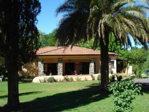 une maison avec un palmier en face dans l'établissement Las Acacias - Posada de Campo, à Villa General Belgrano