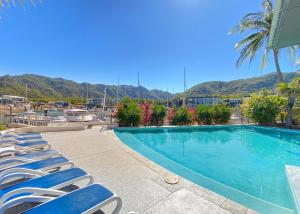 a swimming pool with chairs and mountains in the background at Blue on Blue Studio Room 1242 in Nelly Bay