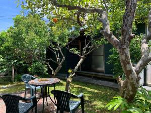 a patio with a table and chairs under a tree at 紀州安兵衛 in Kushimoto