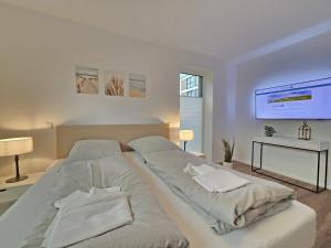 a white bedroom with two beds and a tv at Ferienwohnung Meeresrauschen mit Sauna Haustier erlaubt in Norden
