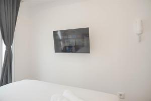 a tv on a white wall in a bedroom at Simply and Cozy Studio at Tokyo Riverside PIK 2 Apartment By Travelio in Rawalembang