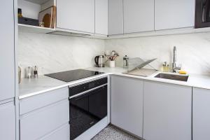 a white kitchen with white cabinets and a sink at Appartement entier avec place de parking in Angoulême +2 photos