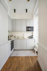 a white kitchen with white cabinets and a wooden floor at Appartement entier avec place de parking in Angoulême