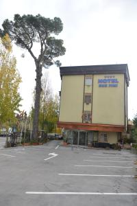 un grande edificio con un albero in un parcheggio di Hotel Due Pini a Melfi