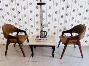 two chairs and a coffee table with a tea kettle on it at Unity Sunrise Resort Statue of Unity Ekta Nagar in Kevadia