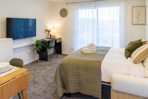 クライストチャーチにあるLuxury Studio With Balcony - Close to Supermarketのベッド、机、テレビのある寝室