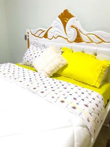 Una cama blanca con un marco de cama amarillo y blanco. en Cozy Residence IV 2bedroom Apartment near Speke Resort, en Munyonyo