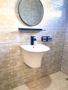 Un baño con un lavabo blanco y un espejo. en Cozy Residence IV 2bedroom Apartment near Speke Resort, en Munyonyo 10 fotos más