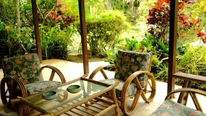 two chairs and a glass table on a porch at Deluxe bedroom at Rumah Sentosa in Kampong Sum Sum
