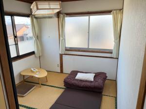 a small room with a bed and a table at ゲストハウスまちかど Guest House MACHIKADO in Ibusuki