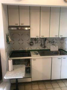 a kitchen with white cabinets and a sink at Monolocale a Grado in Grado