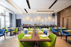 un ristorante con tavoli di legno e sedie verdi di Hampton By Hilton Shenzhen Futian Mangrove Park Apartments a Shenzhen