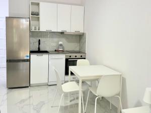 Playa del AguilaにあるGRAN CANARIA Casa Magboss IV i V by Jacek Budekの白いキャビネット、白いテーブルと椅子付きのキッチン