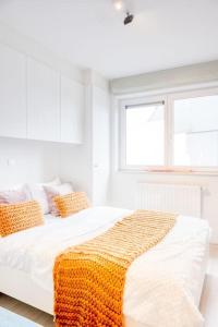 Un dormitorio blanco con una cama con una manta amarilla. en Seaside Serenity Cozy 2-BR Escape, en Blankenberge