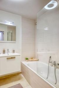 Un baño blanco con bañera y lavabo. en Seaside Serenity Cozy 2-BR Escape, en Blankenberge