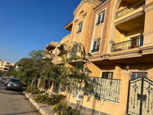 a yellow building with a gate on a street at The Royal Apartment at New Cairo الشقة الملكية بالقاهره الجديدة in Cairo