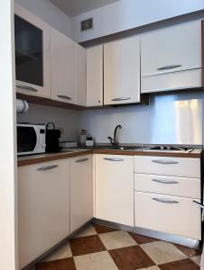 a kitchen with white cabinets and a microwave at Venice Secret Garden view in Venice