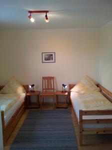 2 camas en una habitación con 2 sillas y una lámpara en "Höper Mittelhof" Ferienhaus Nr 1, en Lemkendorf