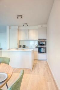 オーステンデにあるSunny Seaview Sanctuary in Ostend w Parkingの白いキャビネットと木製のテーブルのあるキッチン