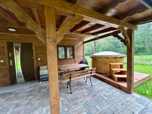 a wooden pavilion with a bench and a hot tub at Gaj za Rzeką GNAP in Prusie