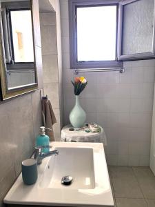 a bathroom with a sink and a vase with flowers at Kiparissi suit in Evdilos +14 photos