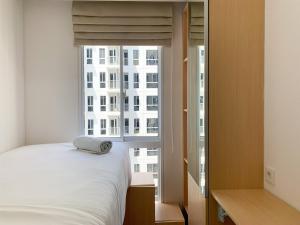 een slaapkamer met een bed en een groot raam bij Relaxing 2BR at 35th Floor Tokyo Riverside PIK 2 Apartment By Travelio in Rawalembang