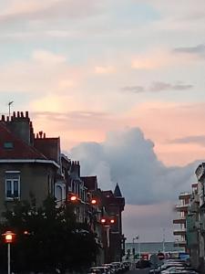 Una calle de la ciudad al atardecer con edificios y semáforos. en Vue sur mer, en Malo-les-Bains