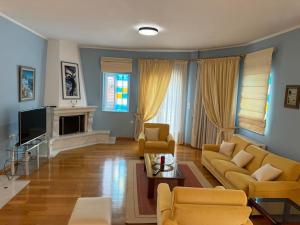a living room with yellow couches and a tv at Sunny and Spacious Luxury House in Pyrgetós