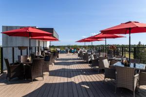 a patio with tables and chairs and red umbrellas at Holiday Inn Express - Grand Island by IHG in Niagara Falls