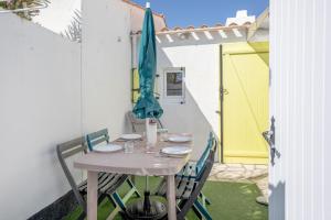 einen Tisch mit Stühlen und einem Sonnenschirm auf einer Terrasse in der Unterkunft Studio piscine partagée in Brétignolles-sur-Mer