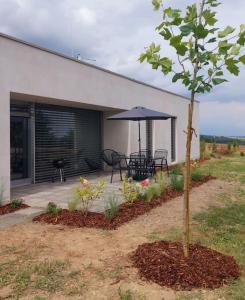a patio with a table and an umbrella and a tree at Pasivní dům uprostřed louky in Bítov