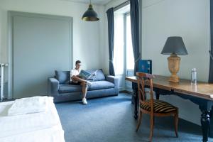 a man sitting on a couch in a room at Vevey Hotel & Guesthouse in Vevey