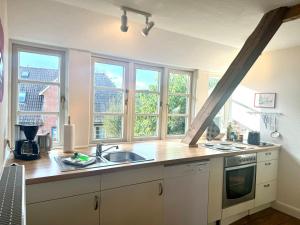 a kitchen with a sink and two windows in it at Altes Standesamt Große Wohnung in Oldsum +14 photos