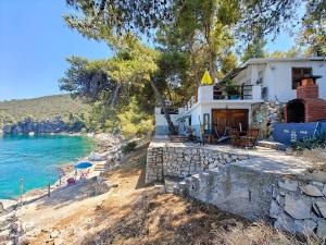 a house on the shore of a body of water at Robinson House Destina in Bogomolje