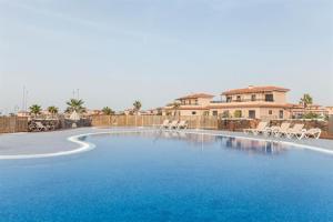 a large swimming pool with chairs and a building at Casa La Ola Majanicho - Monthly Stays in Majanicho
