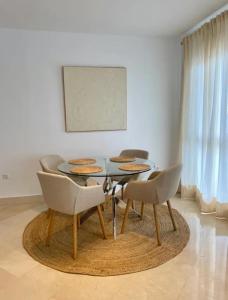 a dining room with a glass table and chairs at Apartamento Puerto Sotogrande in Sotogrande
