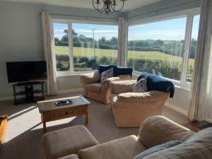 Una sala de estar con sofás y un televisor de pantalla plana. en Cockles Farm Bungalow, en Saltash
