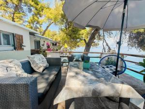 a patio with a table and an umbrella at Robinson House Destina in Bogomolje